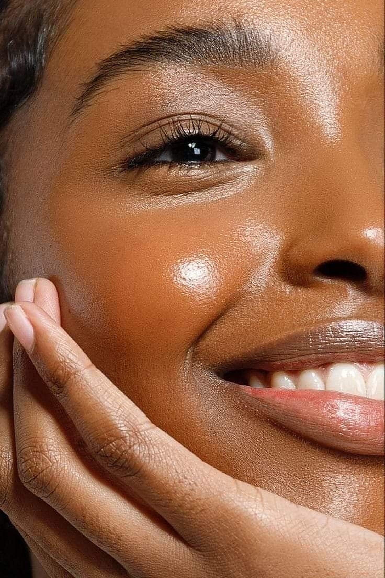 Smiling woman with glowing, hydrated skin touching her cheek