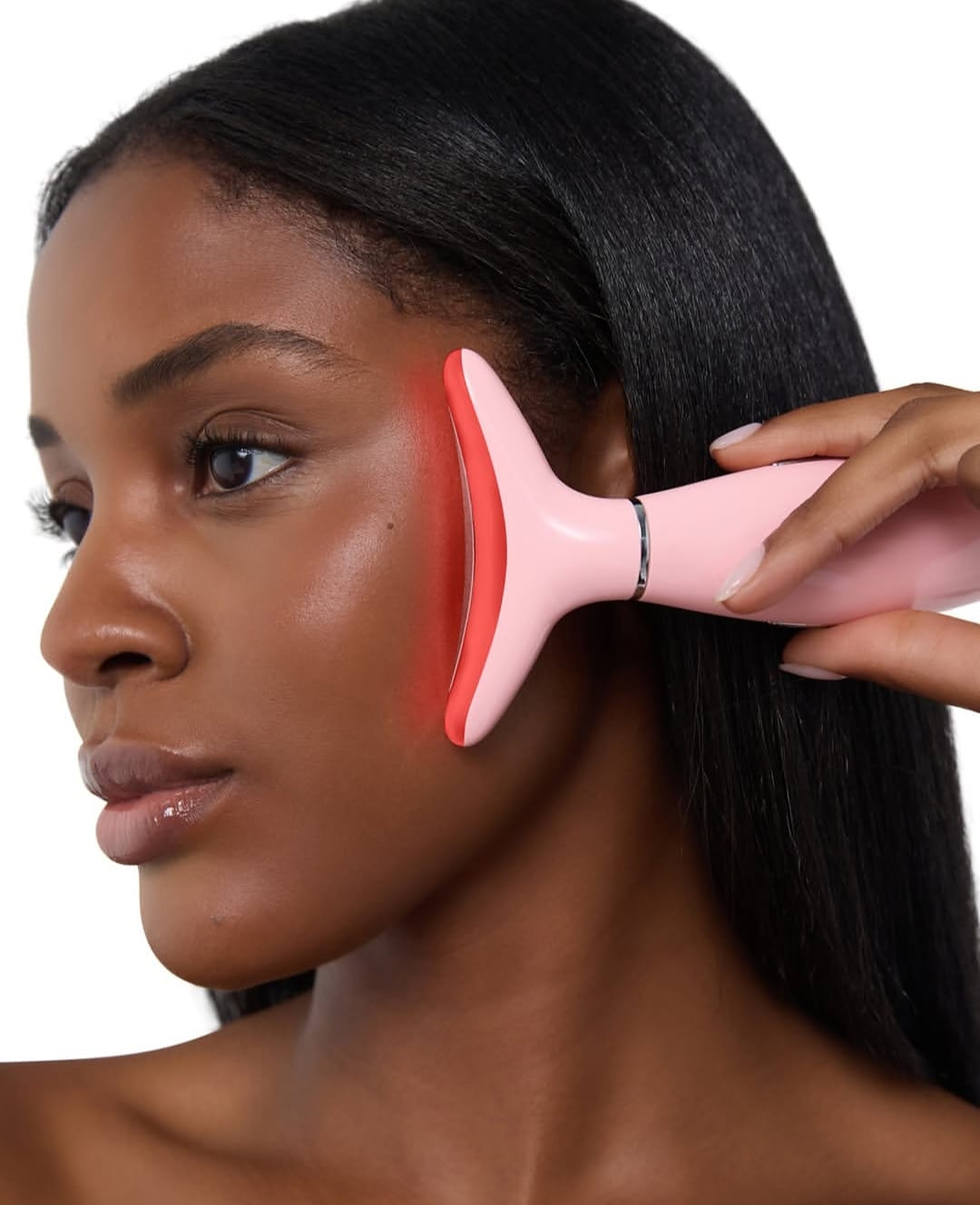 Woman using a pink red-light facial tool along her cheek