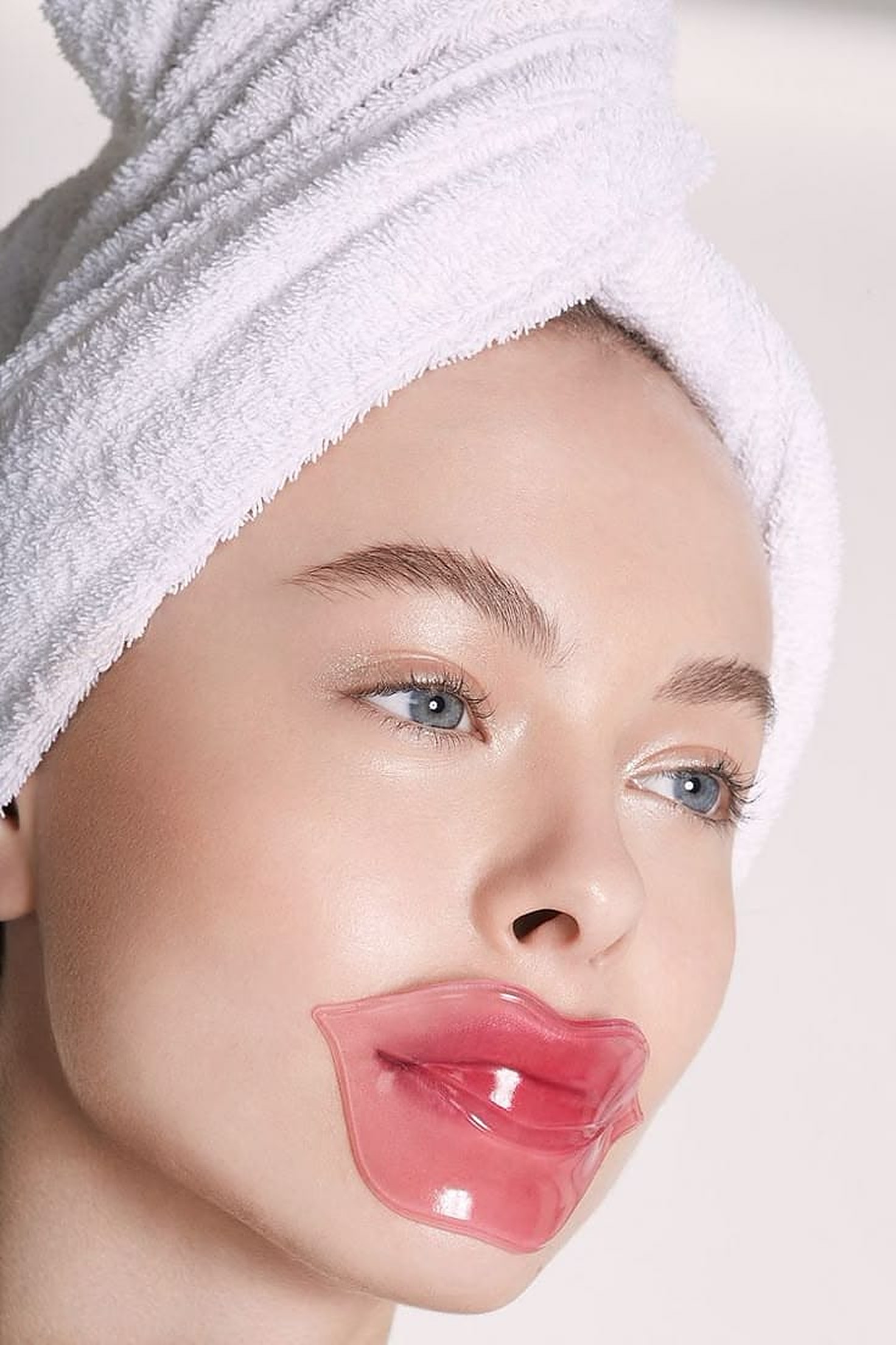 Woman in a towel wrap wearing a pink hydrating lip mask